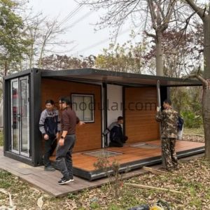 Finalizing the assembly of a modern 20ft expandable container house showing the glass doors and spacious interior entry