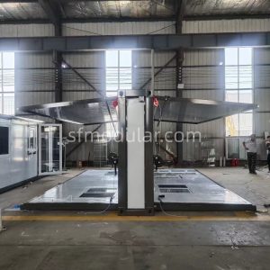 Production stage of small expandable homes showing the folding structural frame and roof mechanism in the factory.