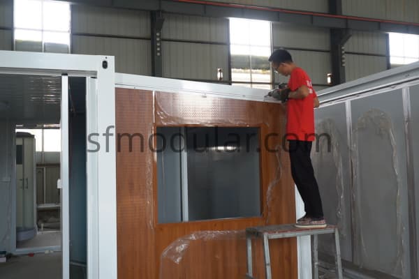Worker checking exterior panel during modular unit assembly