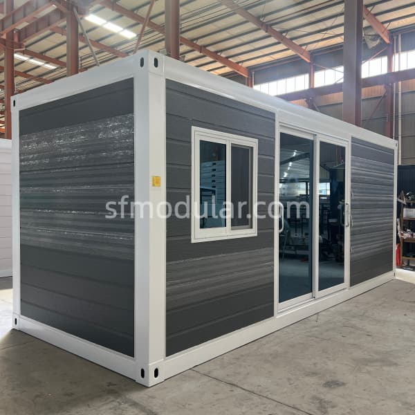 Dark gray backyard granny pod with sliding glass door and white frame shown before delivery