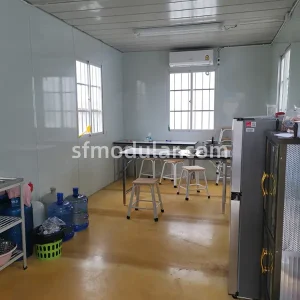 Low cost temporary housing common room and dining area for site accommodation, featuring clean white modular walls.