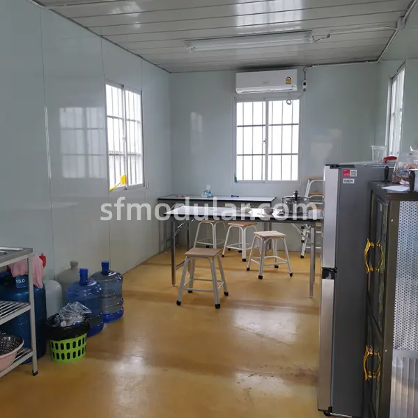 Low cost temporary housing common room and dining area for site accommodation, featuring clean white modular walls.
