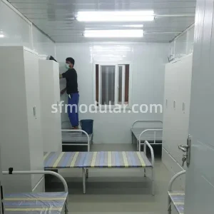 Comfortable temporary housing for construction workers dormitory interior with single beds and storage lockers in a portable prefab unit.